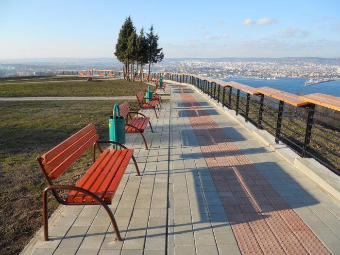 малка алея с пейки и кошчета за боклук гледащи към града